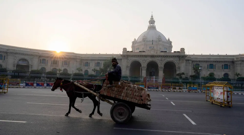 رجل على عربة يجرها حصان يمر في أحد شوارع مدينة لوكنو بولاية براديش الهندية (أ.ب)