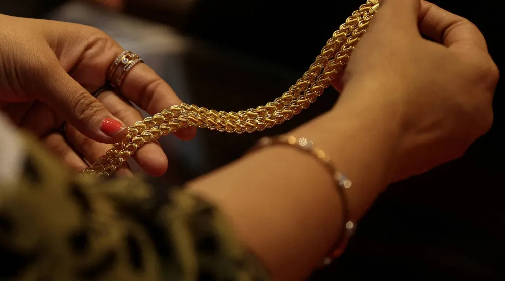 زبونة تحمل سلسلة ذهبية في متجر مجوهرات بمدينة مومباي (رويترز)