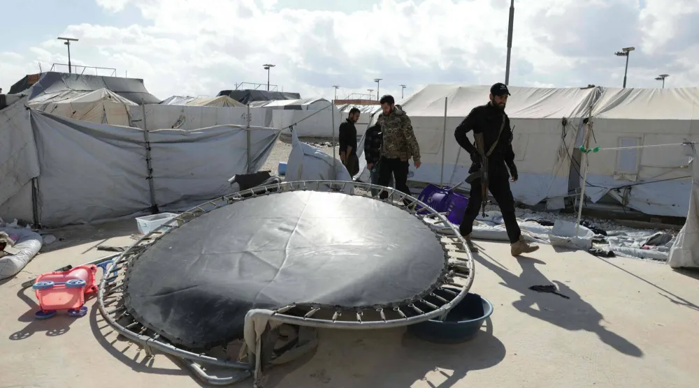 متعلقات سكان مخيم الهول خارج الخيم ويظهر أفراد من القوات الحكومية السورية بعد أن شهد فراراً جماعياً لأقارب مشتبه بانتمائهم لـ«داعش» (أ.ف.ب)