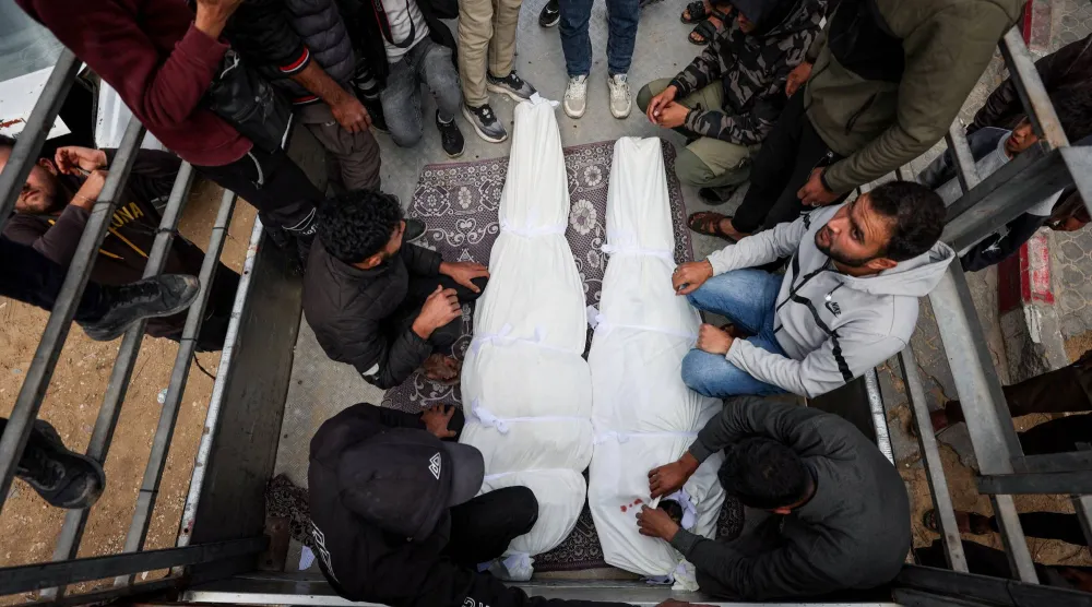 فلسطينيون بجوار جثماني شخصين قُتلا في غارة إسرائيلية على غزة يوم أمس (رويترز)