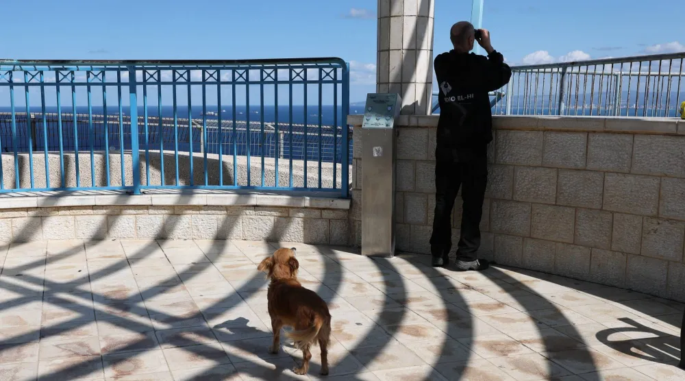 رجل يستخدم منظاراً لمشاهدة البحر الأبيض المتوسط قبل الوصول المتوقع لحاملة الطائرات جيرالد فورد إلى ميناء حيفا (إ.ب.أ)