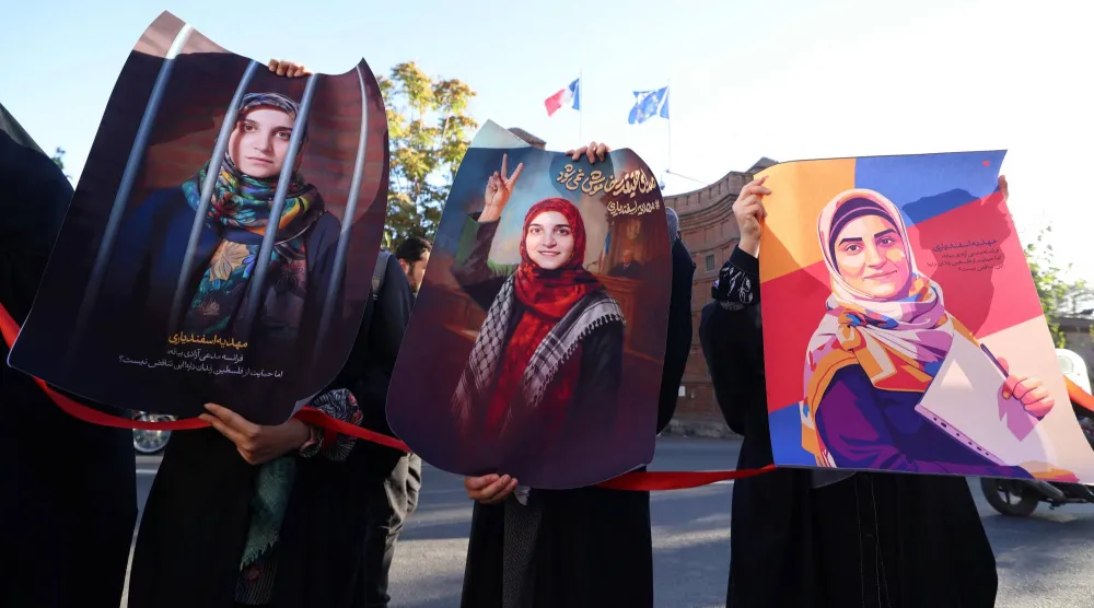 متظاهرون أمام السفارة الفرنسية في طهران يحملون صوراً لمواطنتهم مهدية إسفندياري التي تحاكم في باريس بتهم الإرهاب (أ.ف.ب)