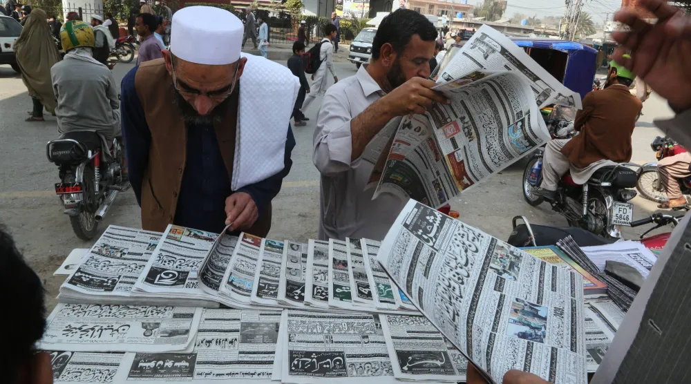 باكستانيون يتابعون في الصحف أخبار الاشتباكات مع أفغانستان في بيشاور أمس (أ.ب)