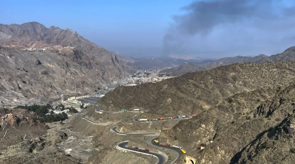 تصاعد الدخان من الجانب الأفغاني بينما تتوقف الشاحنات على جانب الطريق في أعقاب اشتباكات عبر الحدود بين القوات الباكستانية والأفغانية، بالقرب من معبر تورخم الحدودي (أ.ب)