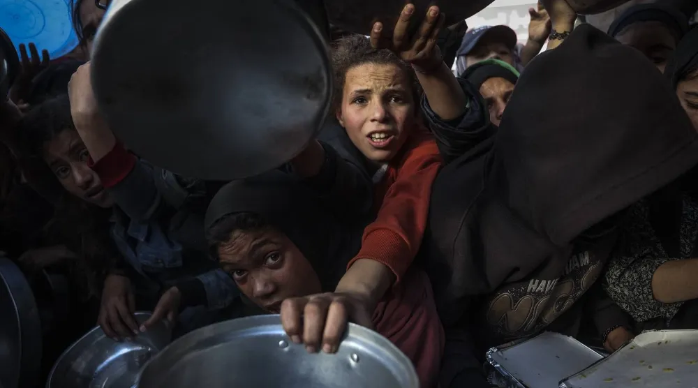 فلسطينيون خلال انتظارهم تلقي الطعام في مطبخ خيري بخان يونس جنوب قطاع غزة (أ.ف.ب)