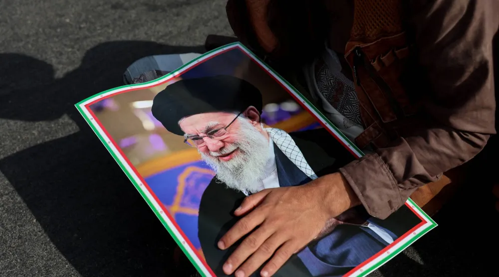 رجل يحمل صورة المرشد الإيراني علي خامنئي (رويترز)