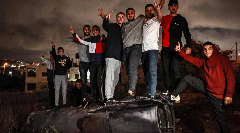 فلسطينيون يحتفلون فوق صاروخ إيراني سقط في رام الله أكتوبر 2024 (أ.ف.ب)