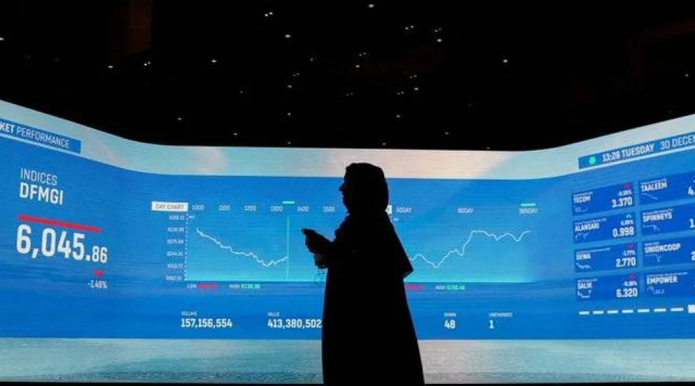 إماراتية تسير إلى جانب شاشة تداول في بورصة دبي (رويترز)