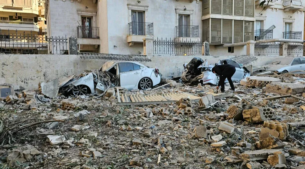 رجل يتفقد حطام سيارة بعد غارة جوية إسرائيلية على ضاحية حارة حريك جنوب بيروت (أ.ف.ب)