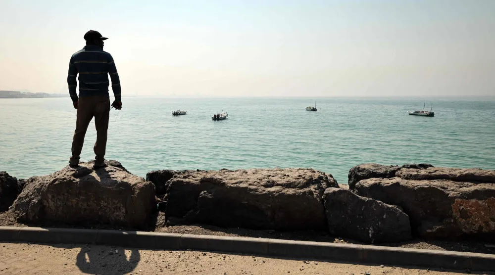 صياد ينظر نحو الأفق بميناء الصيد في العقير على مضيق هرمز بإمارة رأس الخيمة الشمالية (أ.ف.ب)