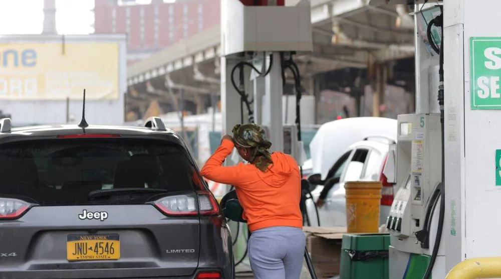 فتاة تستخدم مضخة بنزين بمحطة وقود في مانهاتن بنيويورك (رويترز)