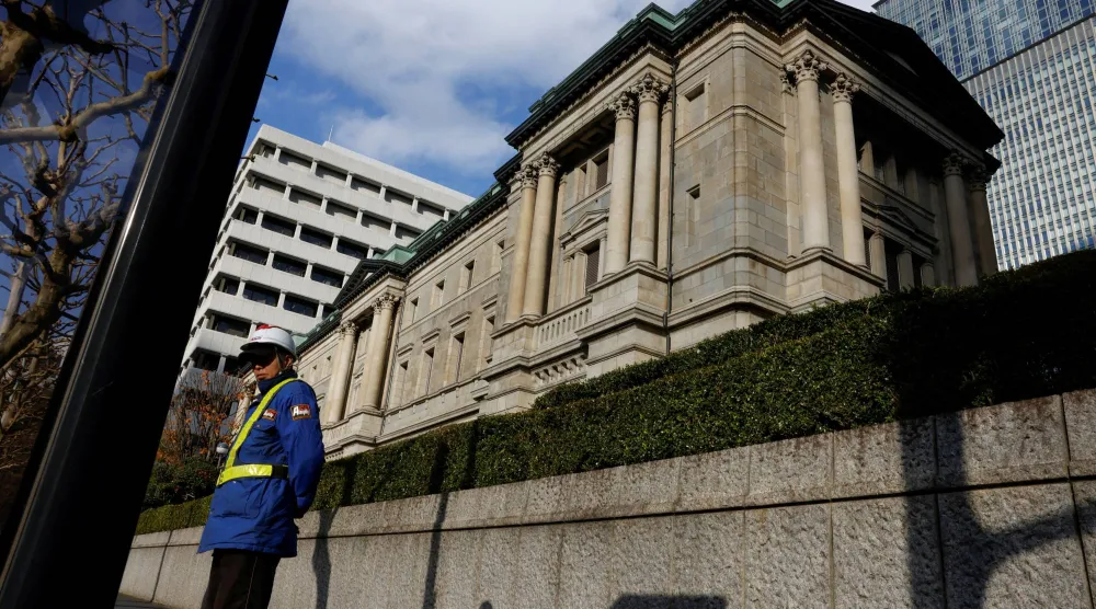 رجل أمن يمر بجوار سور مقر البنك المركزي في العاصمة اليابانية طوكيو (رويترز)