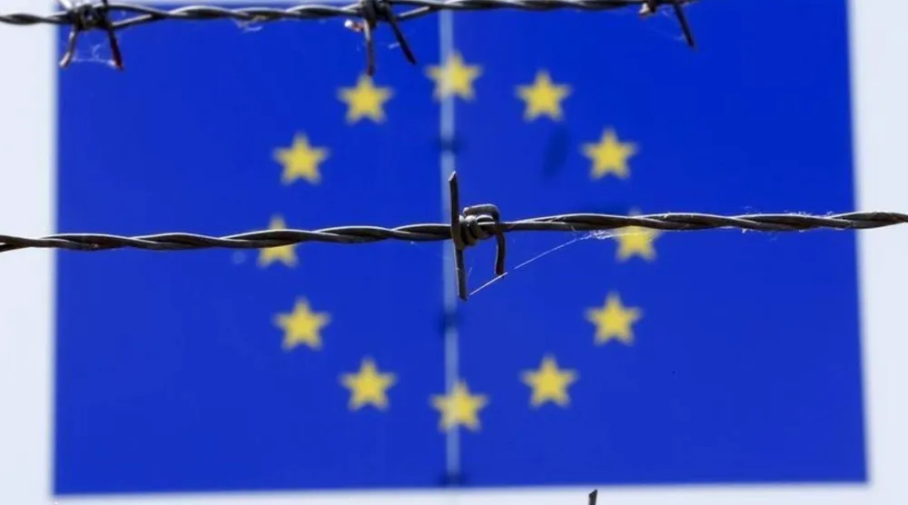 سلك شائك أمام علم الاتحاد الأوروبي (أرشيفية - رويترز)