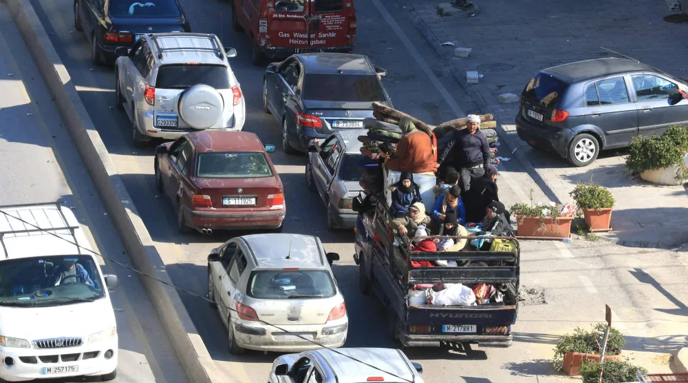 عائلة تحمّل أغراضها في حافلة على الطريق الساحلي لمدينة صيدا التي تزدحم بالسيارات الهاربة من الجنوب (أ.ف.ب)