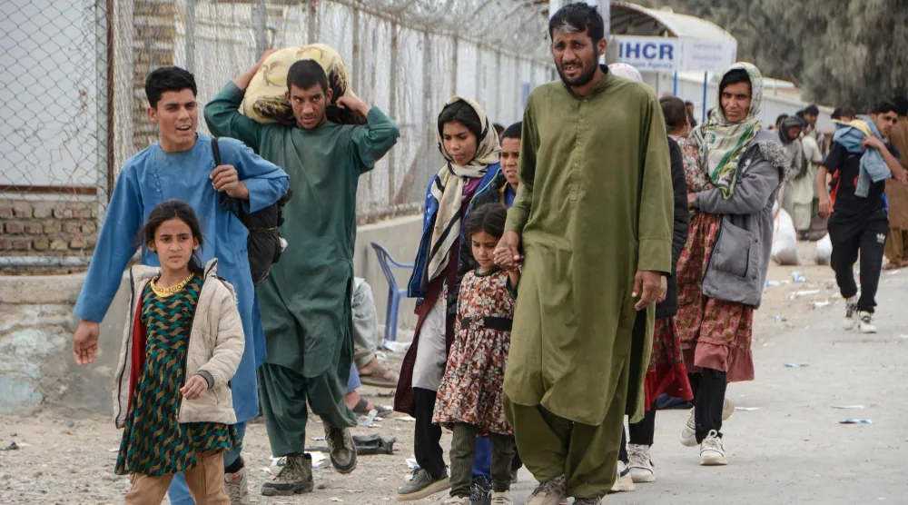 أفغان يعبرون جسر الحرير بولاية نيمروز خلال عودتهم من إيران الاثنين (أ.ف.ب)