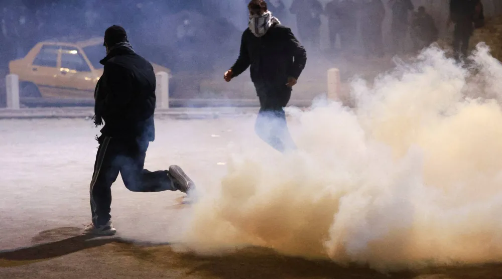 متظاهرون وسط الغاز المسيل للدموع بينما يحاول أنصار جماعات مسلحة عراقية التقدم نحو السفارة الأميركية الواقعة بـ«المنطقة الخضراء» في بغداد (رويترز)