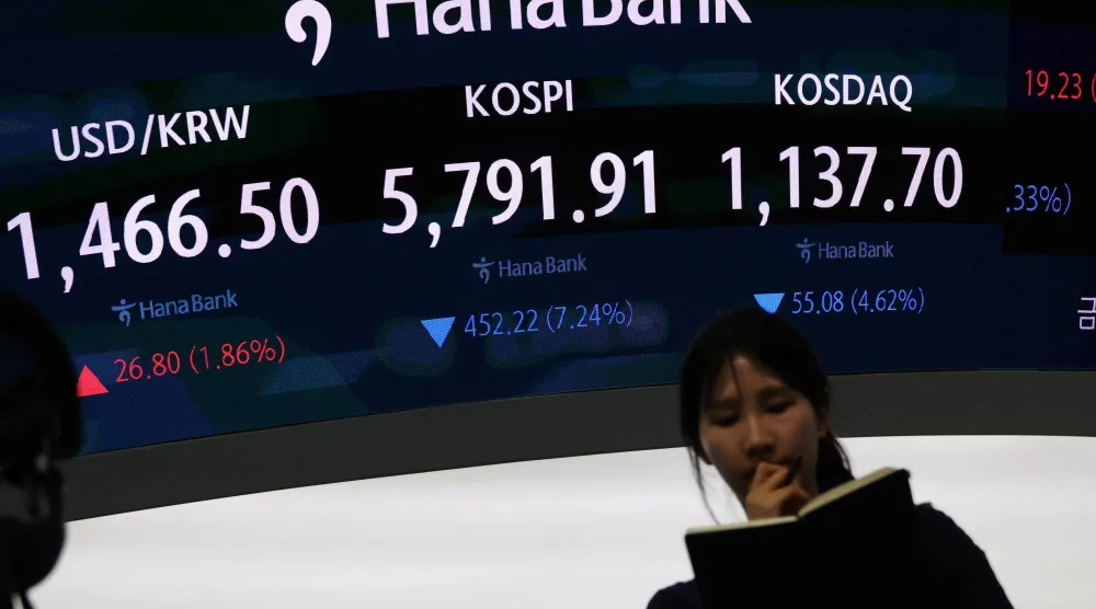 متداولة تقف أمام لوحة تعرض مؤشرات «كوسبي» و«كوسداك» وسعر صرف الدولار في سيول (رويترز)