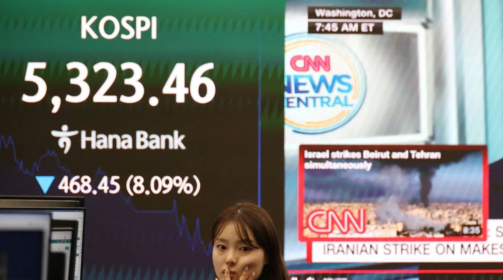  متداولة عملات تعمل أمام لوحة إلكترونية تعرض مؤشر أسعار الأسهم الكوري المركب (كوسبي) (رويترز)