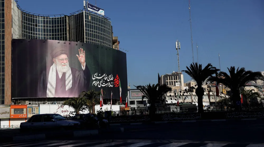 سيارة تمر بجوار لوحة إعلانية للمرشد الإيراني الراحل علي خامنئي في أحد شوارع طهران بإيران بعد اغتياله في غارات جوية إسرائيلية وأميركية يوم السبت (رويترز)