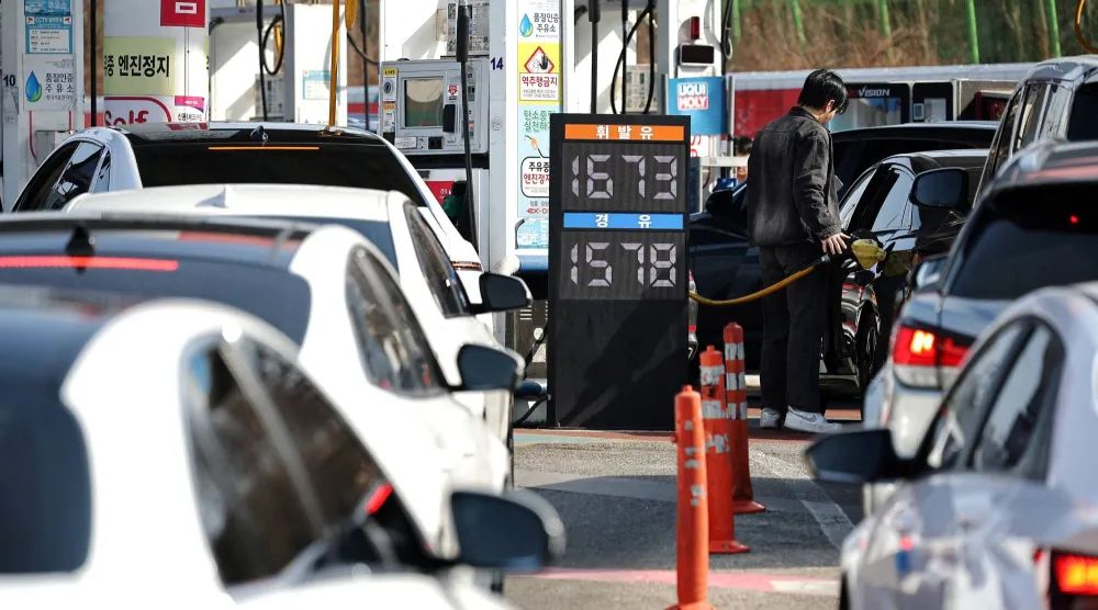 رجل يملأ خزان سيارته بالوقود بينما ينتظر آخرون في طابور بمحطة وقود في سيول (رويترز)