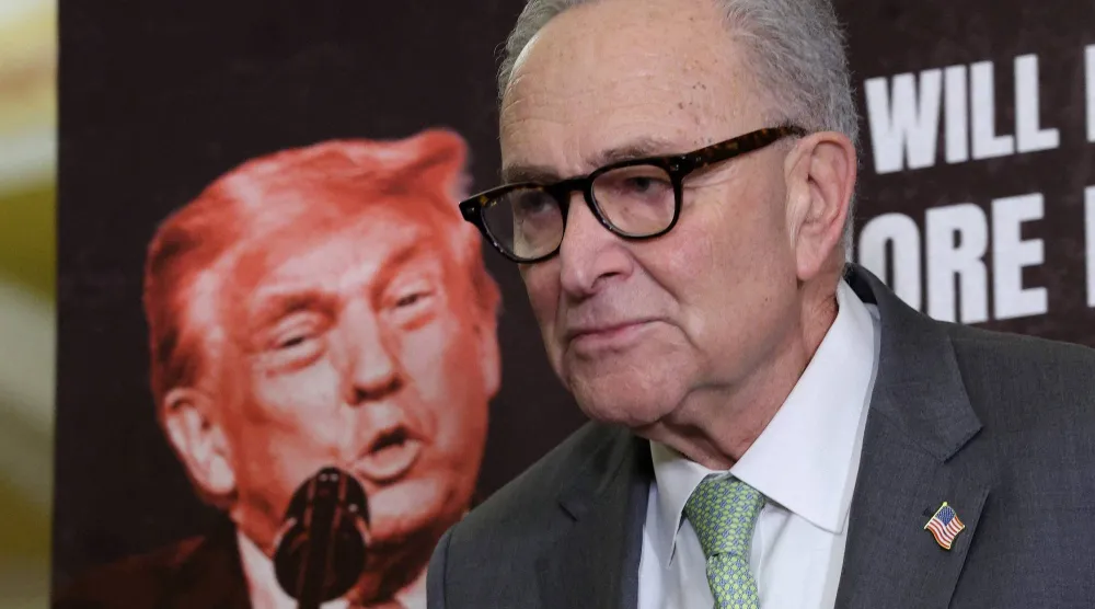 زعيم الديمقراطيين تشاك شومر يتحدث ووراءه صورة ترمب في الكونغرس في 3 مارس 2025 (أ.ف.ب)