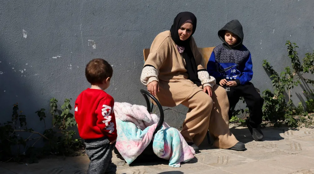 امرأة نازحة مع أطفالها تجلس خارج مدرسة في بيروت تحولت إلى ملجأ في أعقاب تصعيد عسكري بين «حزب الله» وإسرائيل (رويترز)