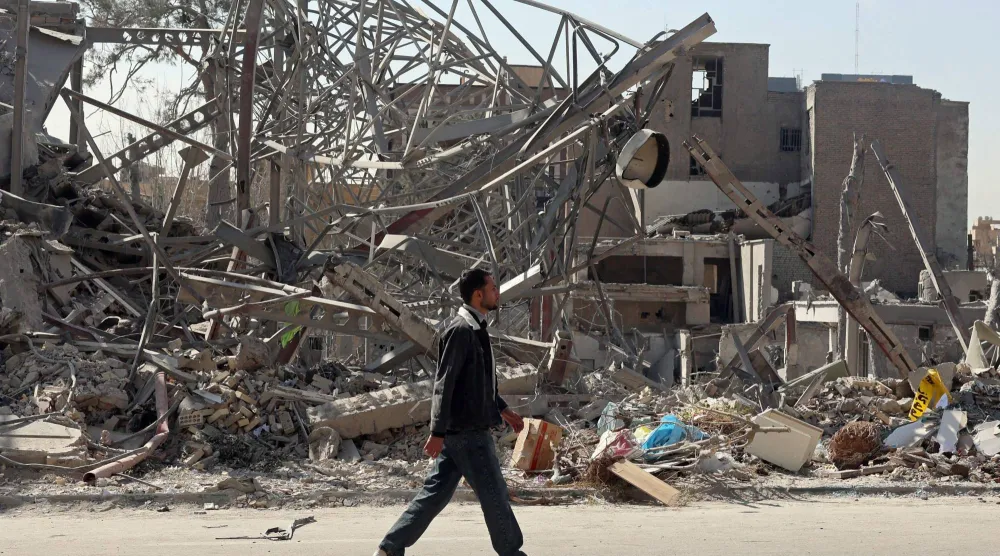 رجل يسير وسط طهران يوم الأربعاء بجوار مبانٍ مدمرة عقب غارات جوية أميركية - إسرائيلية (أ.ف.ب)