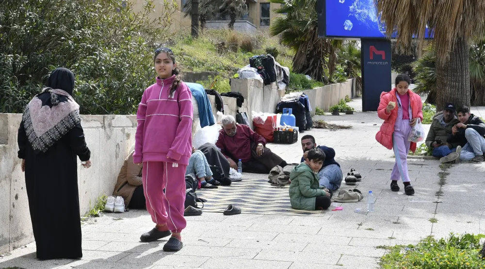 يجلس سكان نازحون على الأرض في بيروت بعد فرارهم من منازلهم بجنوب لبنان وضاحية بيروت الجنوبية (إ.ب.أ)