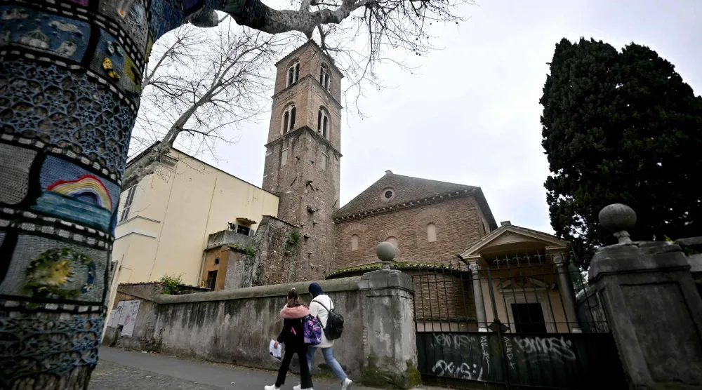 Pedestrians walk past the Basilica of Santa Agnese Outside the Walls as a marble bust is displayed inside after being identified as a work by Michelangelo Buonarroti after centuries without attribution, following a decade of archival research by Italian researcher Valentina Salerno in Rome on March 4, 2026. (AFP)