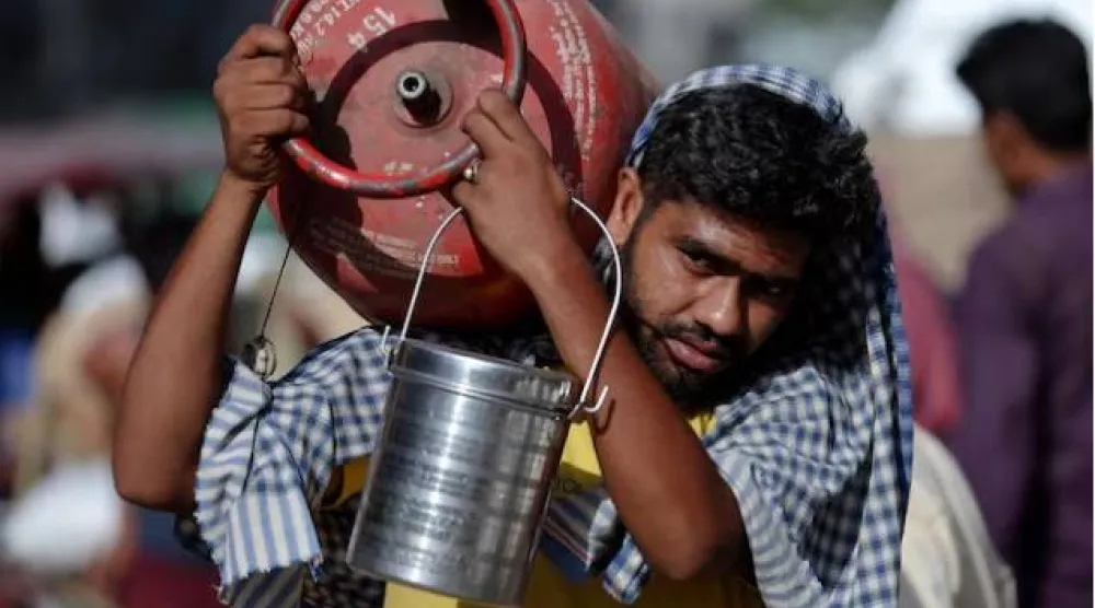 رجل يحمل قارورة غاز البترول المسال على كتفه في سوق جملة بالأحياء القديمة في دلهي (رويترز)