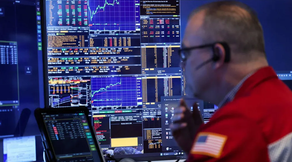 متداول يراقب شاشات تعرض مؤشرات الأسهم في بورصة نيويورك (أ.ف.ب)