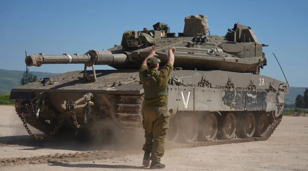 جندي إسرائيلي يوجه دبابة أثناء تعزيزات عسكرية في منطقة محاذية مع جنوب لبنان (أ.ب)