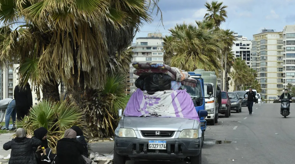 نازحون يجلسون بجوار ممتلكاتهم على رصيف في بيروت 4 مارس 2026 بعد فرارهم من جنوب لبنان والضاحية الجنوبية إثر إنذارات وغارات إسرائيلية (إ.ب.أ)