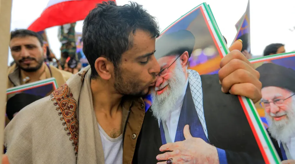 Yemen'in ele geçirilen başkenti Sana'da bir Husi üyesi, Hamaney'in fotoğrafını öpüyor (AFP)