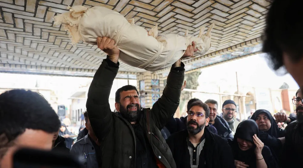 رجل يحمل جسد زينب صاحبي الطفلة البالغة من العمر عامين والتي قُتلت في غارة جوية على طهران (رويترز)