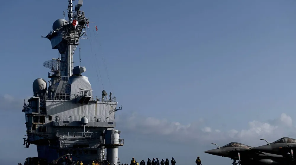 جنود فرنسيون يقفون بالقرب من مقاتلة «رافال» على متن حاملة طائرات «شارل ديغول» (أ.ف.ب)