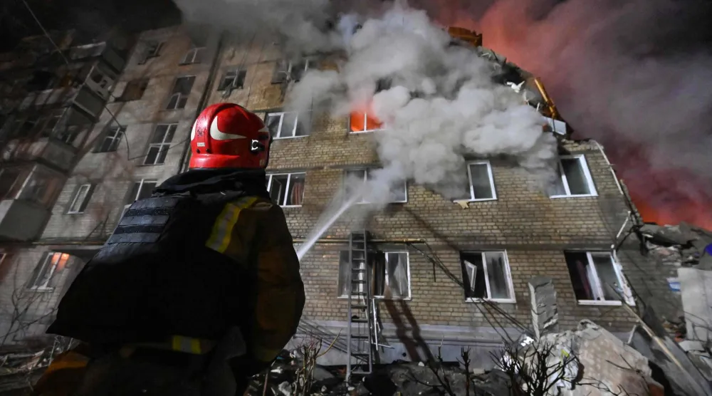 A firefighter extinguishes a blaze at a five-story residential building in Kharkiv on March 7, 2026, after it was partially destroyed by a Russian strike amid the Russian invasion of Ukraine. (Photo by SERGEY BOBOK / AFP)