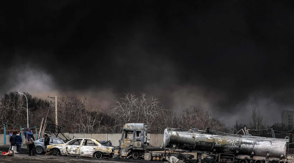 A dark smoke cloud engulfs destroyed vehicles near an ongoing fire following an overnight airstrike on the Shahran oil refinery in northwestern Tehran on March 8, 2026. (AFP)