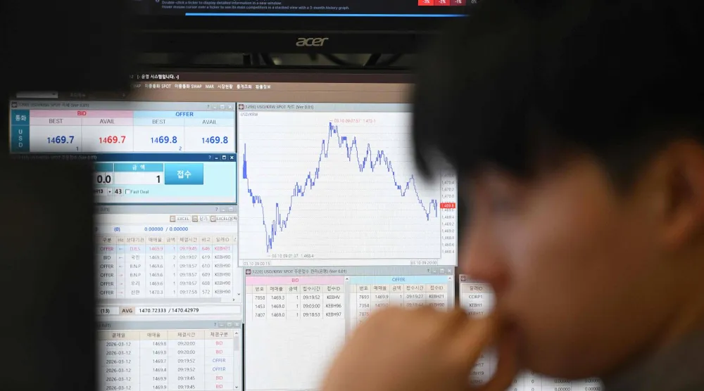 تاجر عملات يراقب أسعار الصرف في غرفة تداول العملات الأجنبية بمقر بنك هانا في سيول (أ.ف.ب)