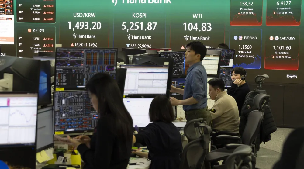 يعمل متداولون كوريون جنوبيون أمام شاشات تعرض مؤشرات الأسهم في بنك هانا بسيول (إ.ب.أ)