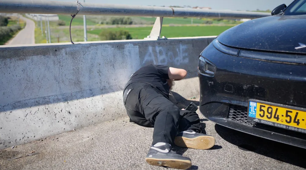 مواطن يتفادي بينما يدوي صوت صافرات الإنذار في منطقة بين القدس وتل أبيب (أ.ب)