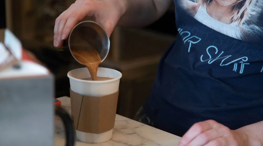 إحدى العاملات في مقهى كندي تصب القهوة للزبون (أرشيفية - أ.ف.ب)