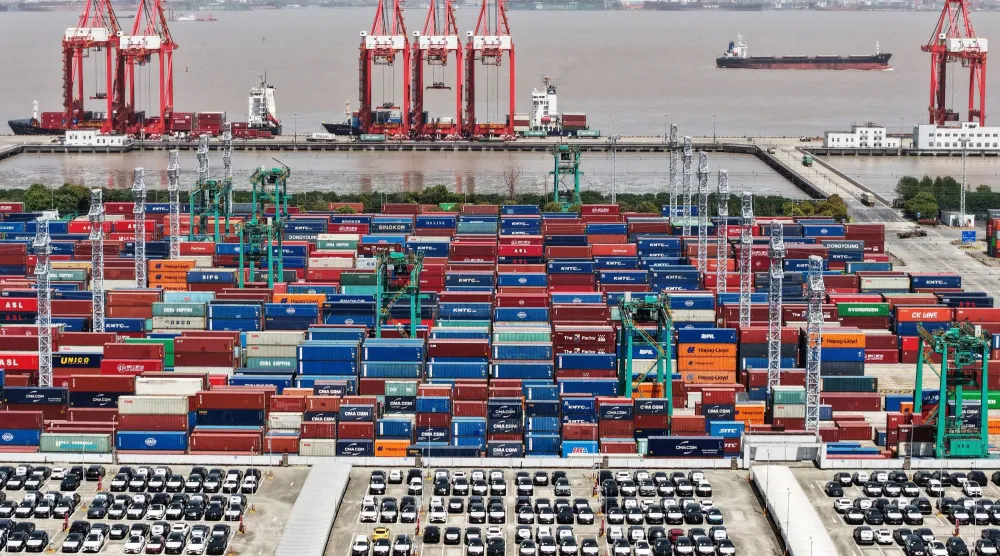 آلاف الحاويات والسيارات الكهربائية المعدَّة للتصدير في ميناء شنغهاي الصيني (رويترز)