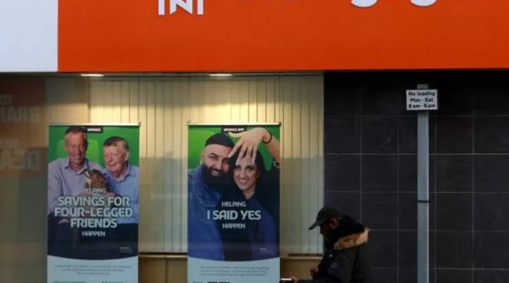 متسوق يمرُّ أمام إعلان للرهن العقاري معروض على نافذة في سندرلاند (رويترز)