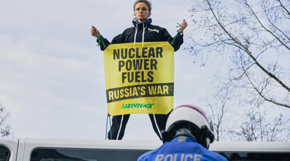 ناشط من منظمة «غرينبيس» يحمل لافتة على سطح شاحنة خلال احتجاج خارج قمة الطاقة النووية التابعة للوكالة الدولية للطاقة الذرية في باريس (أ.ب)