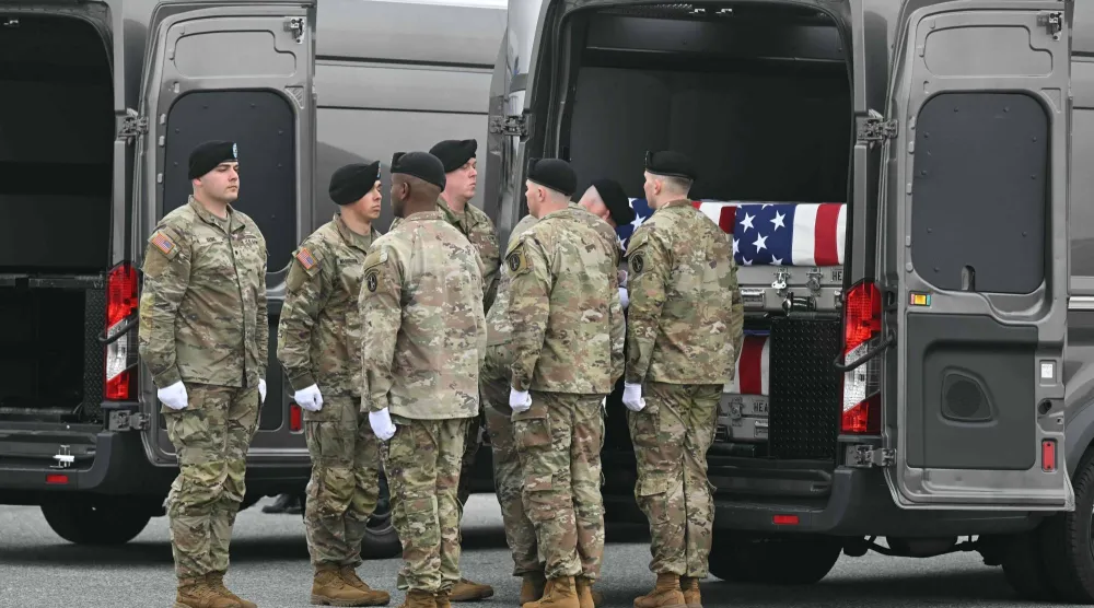 فريق من الجيش الأميركي يقف أمام صناديق نقل رفات الجنود المغطاة بالأعلام خلال مراسم رسمية في ديلاوير (أ.ف.ب)