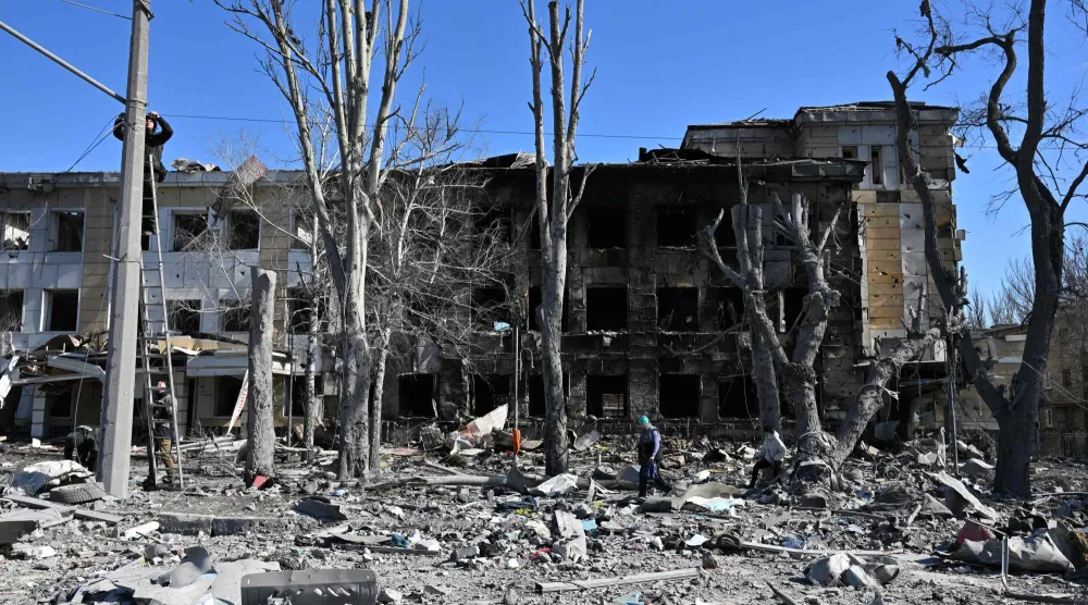 عمال يصلحون الأسلاك أمام عيادة أطفال متضررة في أعقاب قصف حديث وصفه مسؤولون بأنه ضربة عسكرية أوكرانية في دونيتسك الخاضعة للسيطرة الروسية (أ.ف.ب)