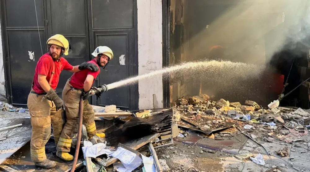 Sivil savunma ekipleri, Beyrut’un güney banliyölerinde İsrail’in hedef aldığı bir binada çıkan yangını söndürmeye çalışıyor. (Reuters)