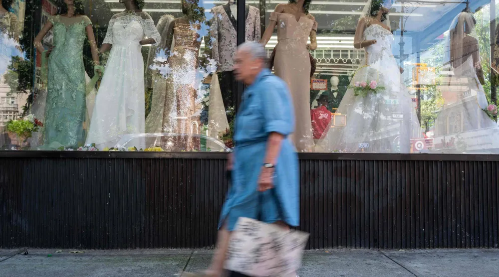 امرأة تمر أمام واجهة متجر تعرض فساتين في بروكلين (أ.ف.ب)