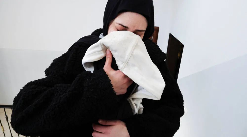 ملك بعيرات تشم رائحة زوجها ثائر حمايل على السترة التي تركها قبل مقتله خلال هجوم شنه مستوطنون إسرائيليون على الفلسطينيين (رويترز)